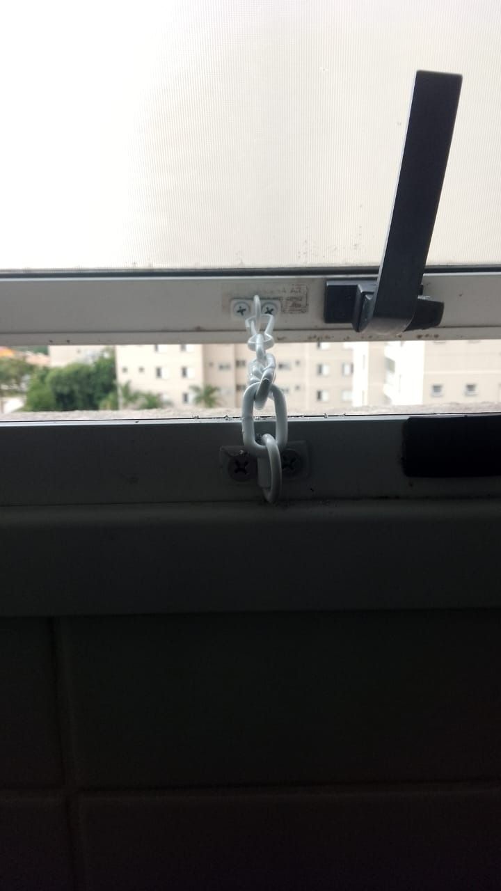 Janela basculante com a abertura limitada por corrente fixada no caixilho
