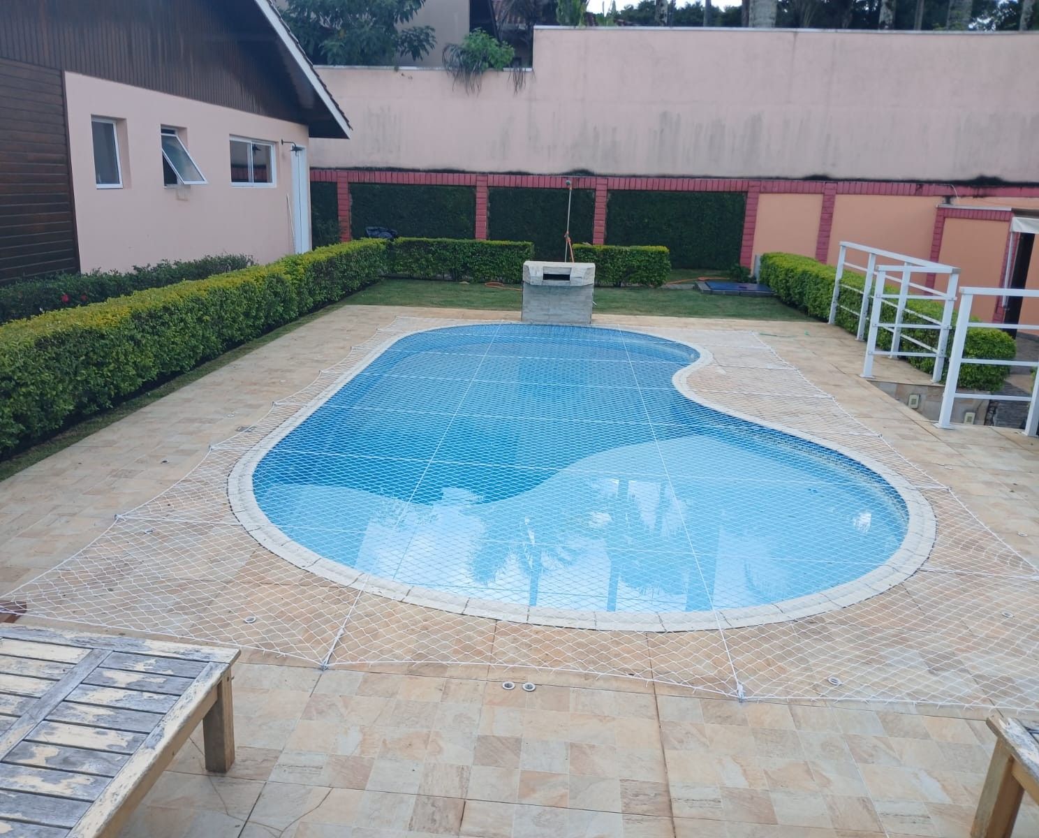 Piscina em formato orgânico coberta por rede de proteção branca