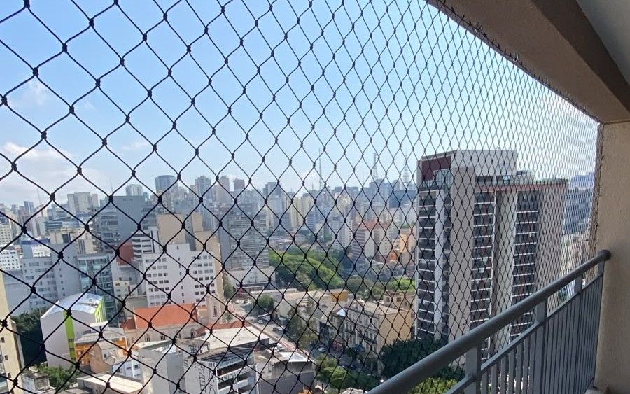 Sacada de apartamento com rede de proteção preta e vista da cidade