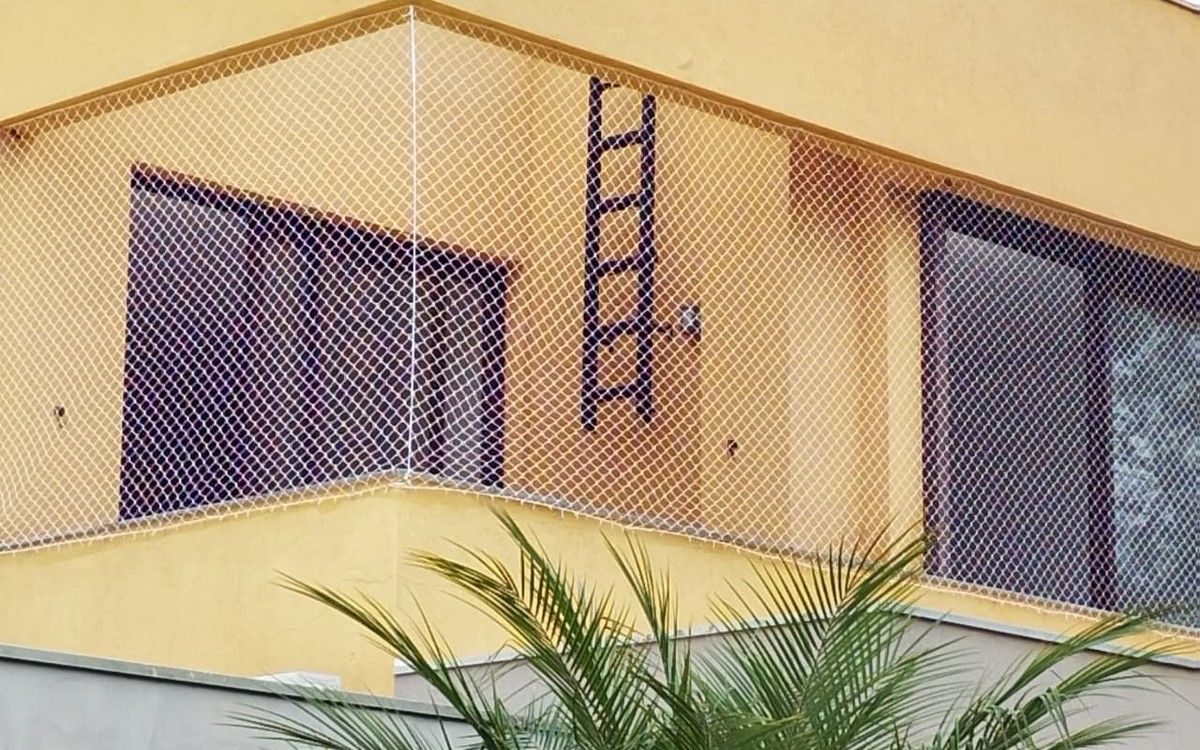 Varanda de casa com rede de proteção branca instalada no vão