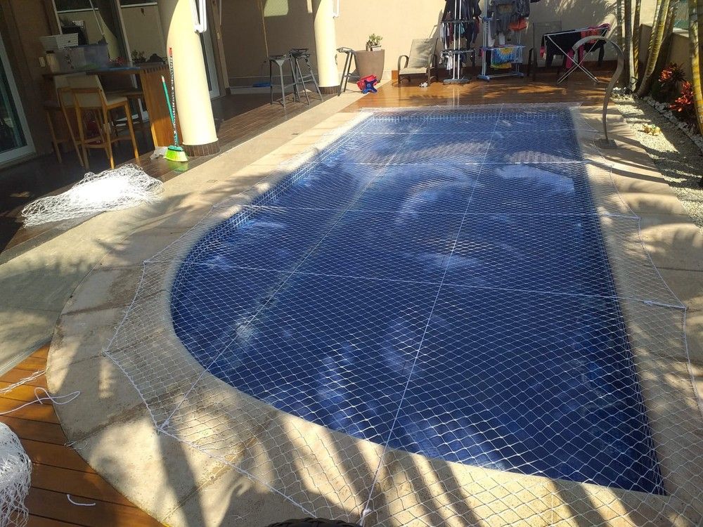 Piscina coberta por rede de proteção azul tensionada sobre a água